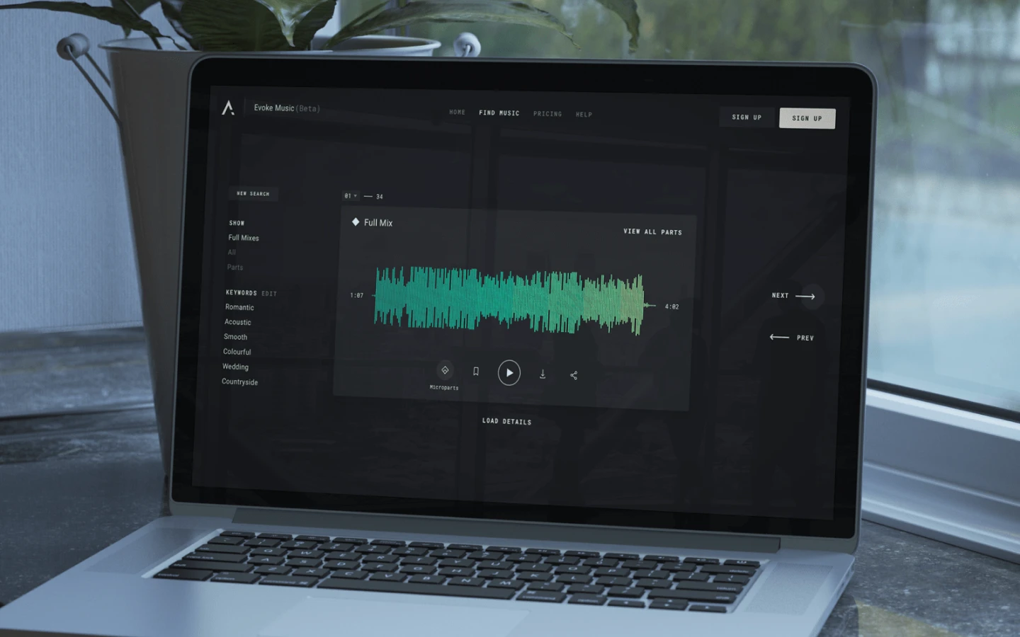 A laptop with the Evoke Music website open sitting on a bench.